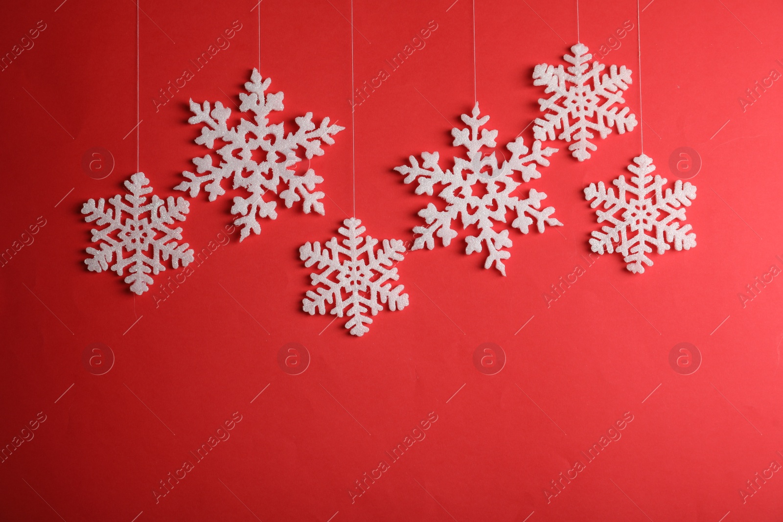 Photo of Beautiful decorative snowflakes hanging on red background