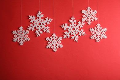 Photo of Beautiful decorative snowflakes hanging on red background