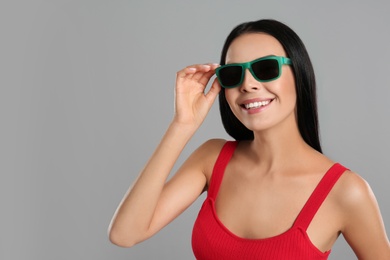 Beautiful woman wearing sunglasses on grey background