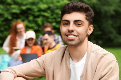 Photo of Students learning together in park. Portrait of happy young man outdoors, selective focus