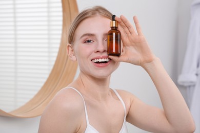 Young woman with bottle of essential oil in bathroom