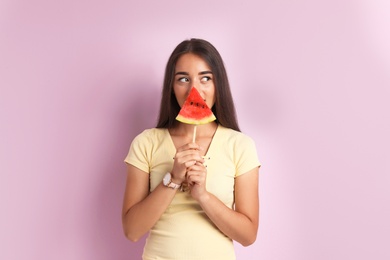 Beautiful young woman posing with watermelon on color background