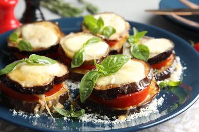 Baked eggplant with tomatoes, cheese and basil on table, closeup