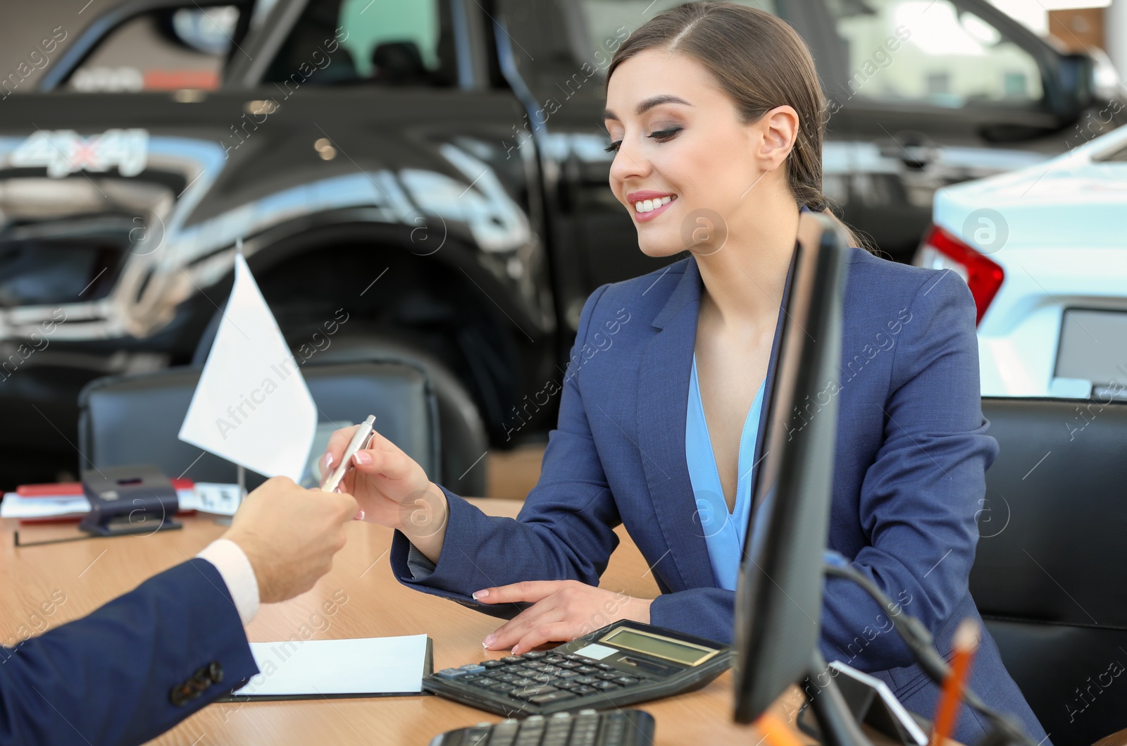 Photo of Young woman signing documents in car salon