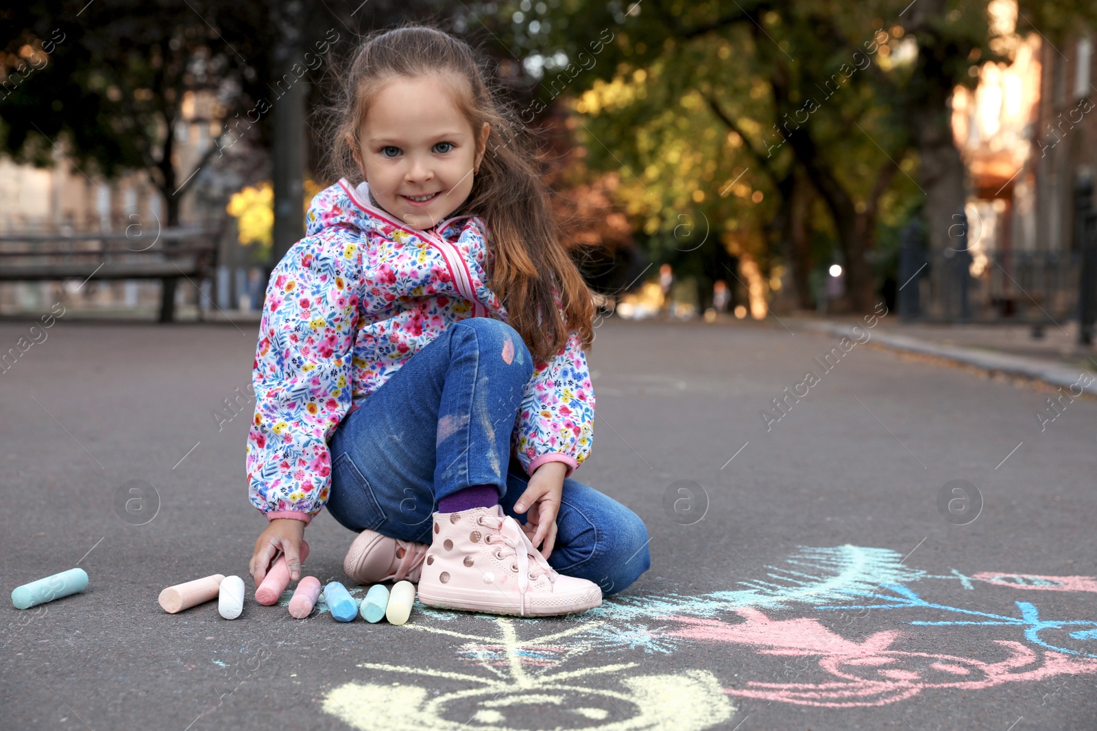 Photo of Child drawing family with chalk on asphalt