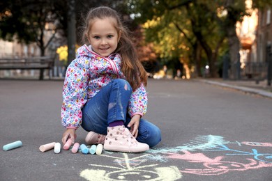 Child drawing family with chalk on asphalt