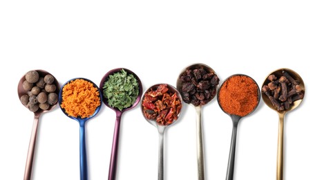 Metal spoons with different spices on white background, top view