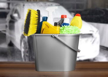 Bucket with cleaning supplies on wooden surface at car wash