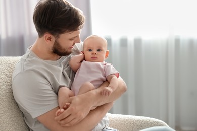 Photo of Father with his cute baby in armchair at home, space for text