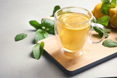 Photo of Glass cup with hot tea and lemon on table. Space for text