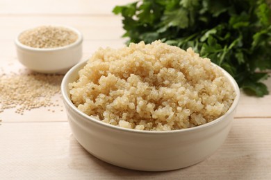 Photo of Tasty quinoa porridge in bowl on light wooden table, closeup