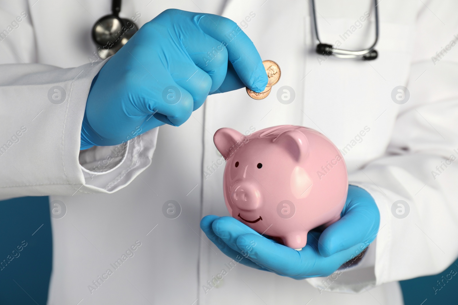 Photo of Doctor putting coins into piggy bank, closeup. Medical insurance