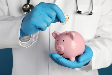 Doctor putting coins into piggy bank, closeup. Medical insurance