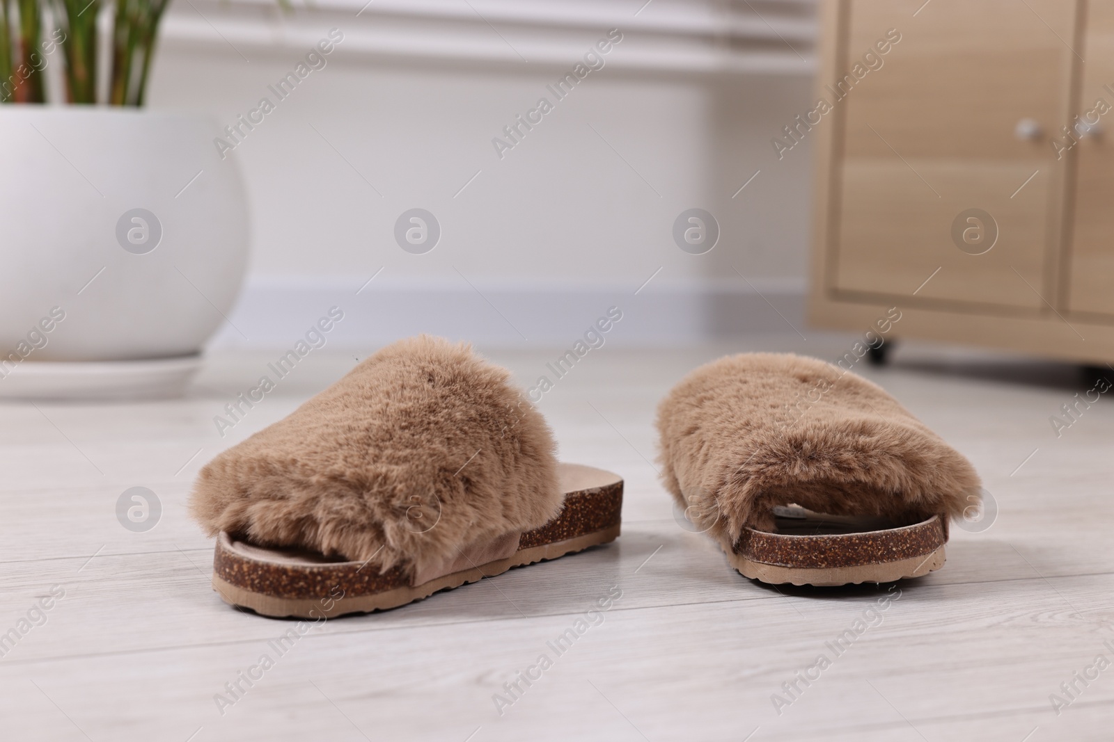 Photo of Soft slippers on light wooden floor indoors, closeup