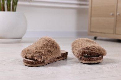 Photo of Soft slippers on light wooden floor indoors, closeup