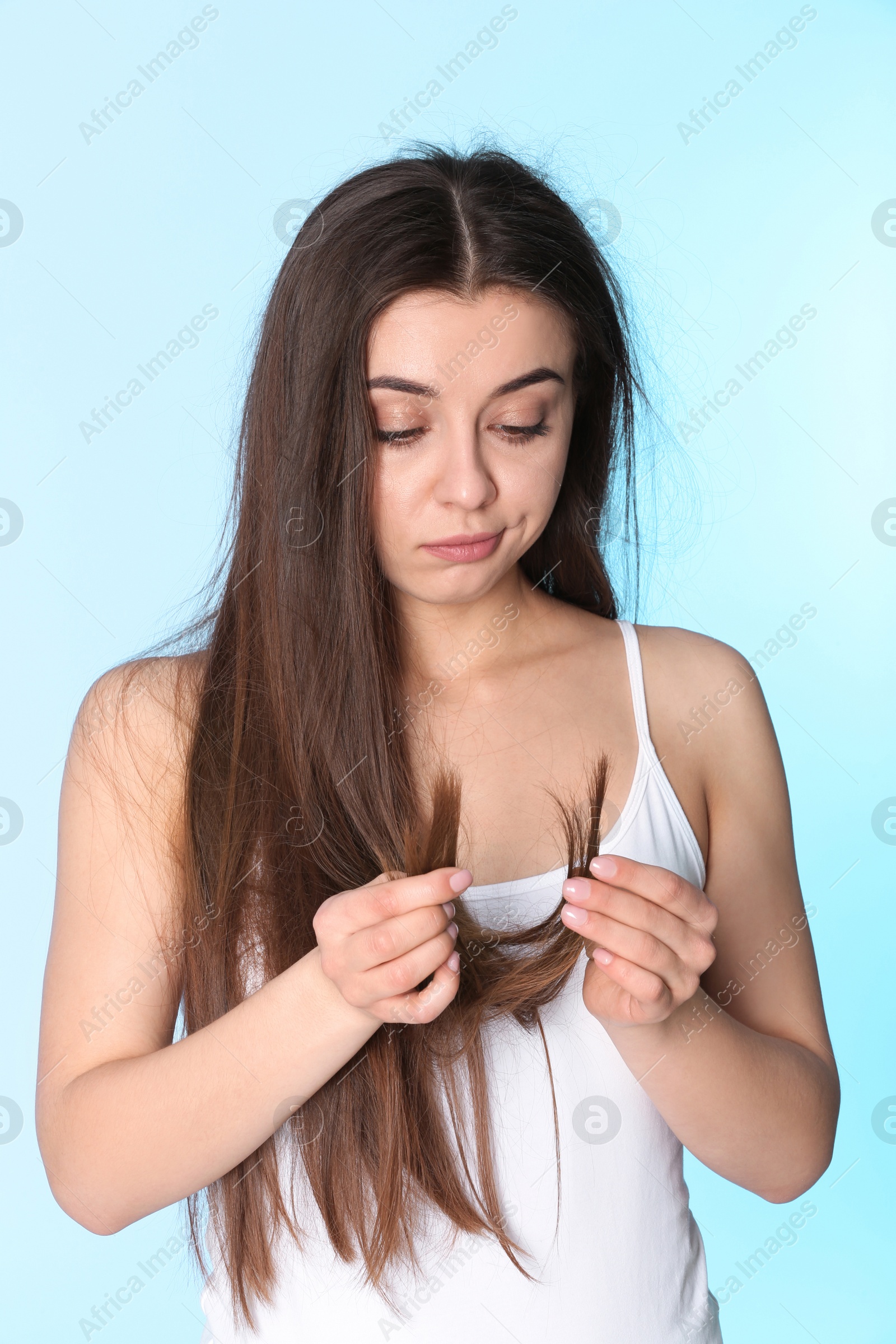 Photo of Emotional woman with damaged hair on color background. Split ends