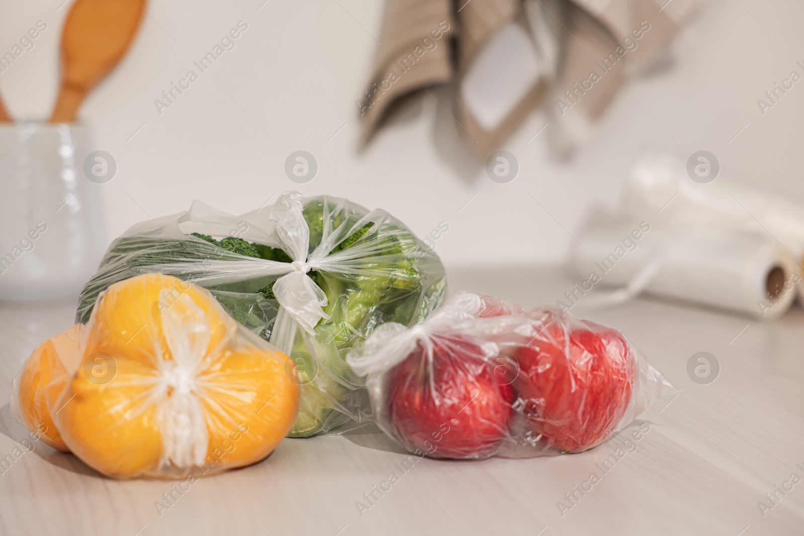 Photo of Plastic bags with fresh products on white table