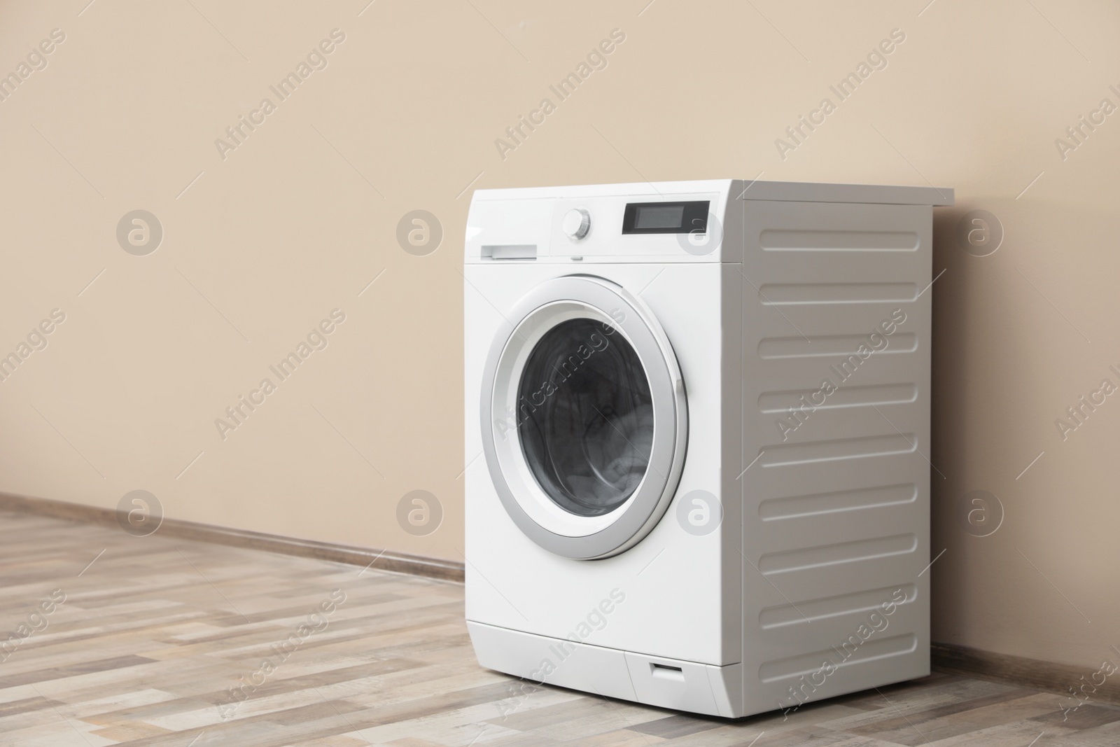 Photo of Modern washing machine with laundry near color wall, space for text