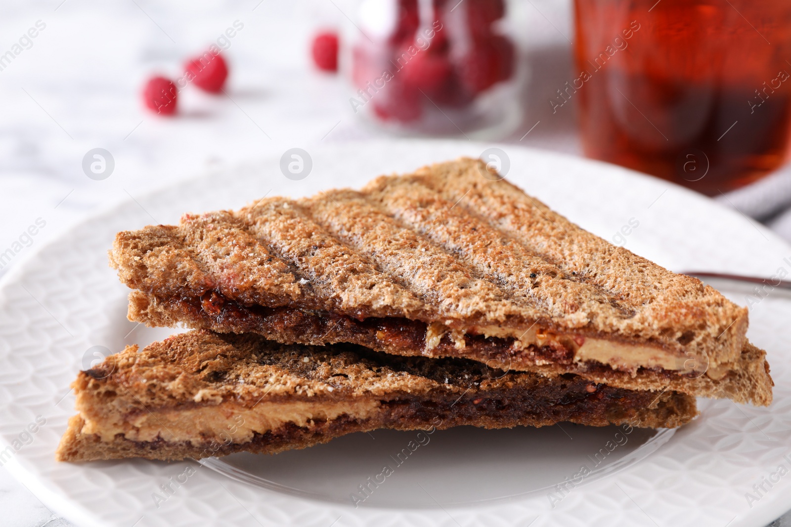 Image of Tasty sandwiches with raspberry jam and peanut butter for breakfast on table, closeup