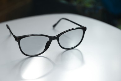 Photo of Stylish black eye glasses on white table, closeup