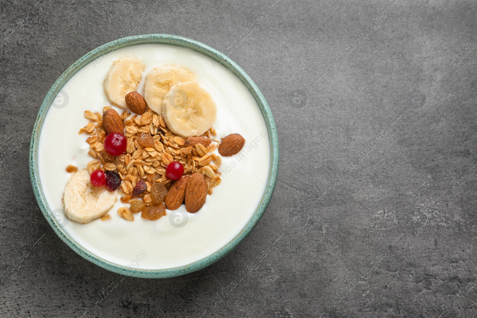 Photo of Bowl with yogurt, banana and granola on table, top view