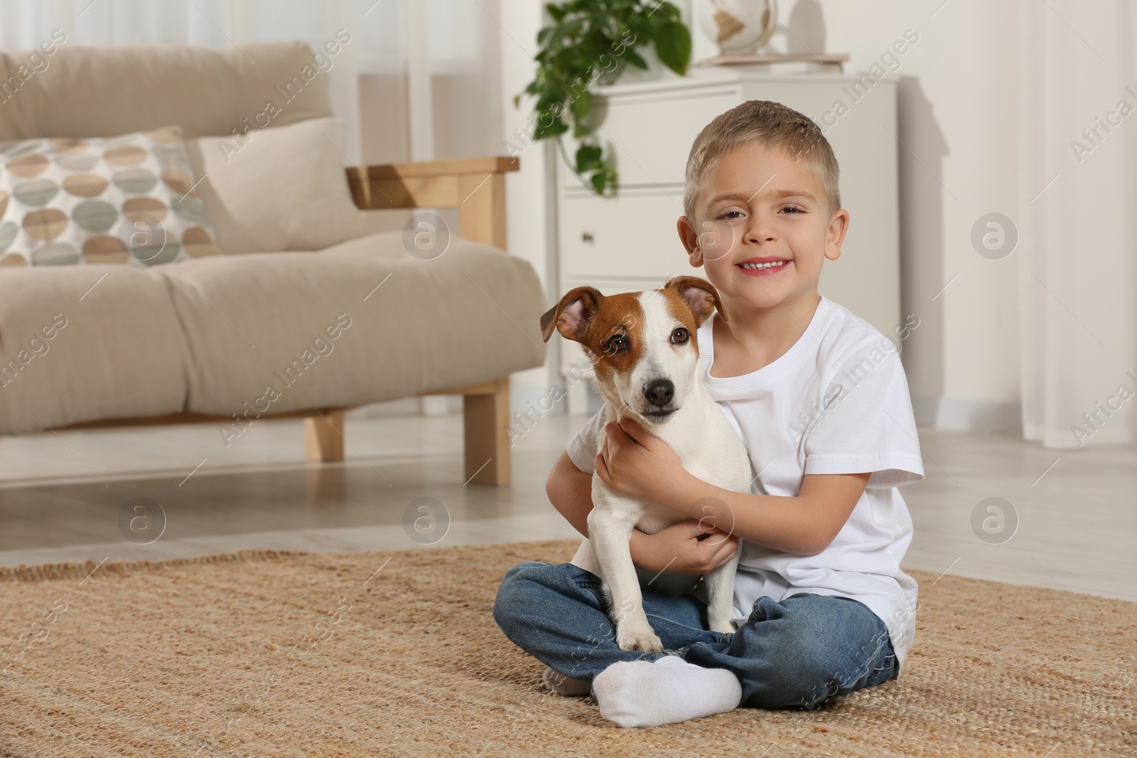 Photo of Little boy with his cute dog on floor at home, space for text. Adorable pet