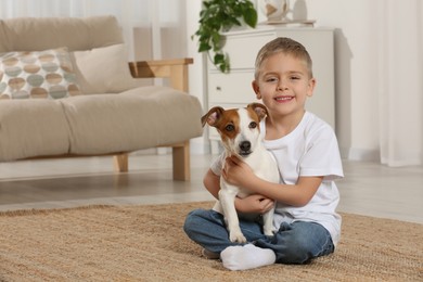Photo of Little boy with his cute dog on floor at home, space for text. Adorable pet