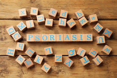 Photo of Word Psoriasis made of cubes with letters on wooden table, flat lay