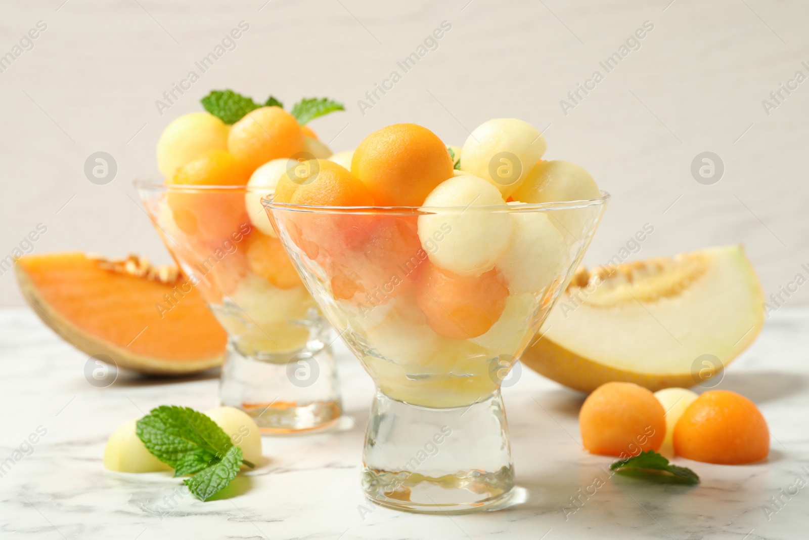 Photo of Melon balls and mint on white marble table