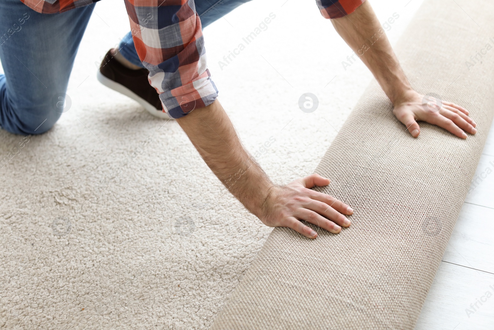Photo of Man rolling out new carpet flooring in room