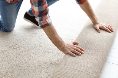 Photo of Man rolling out new carpet flooring in room