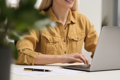 Woman working on laptop at white desk in office, closeup