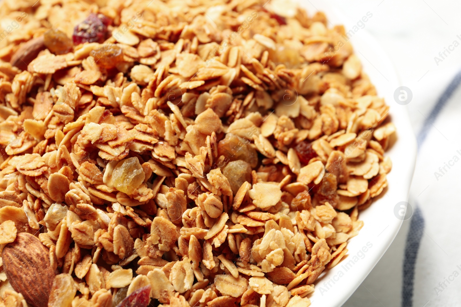 Photo of Tasty muesli with raisins on table, closeup. Healthy breakfast