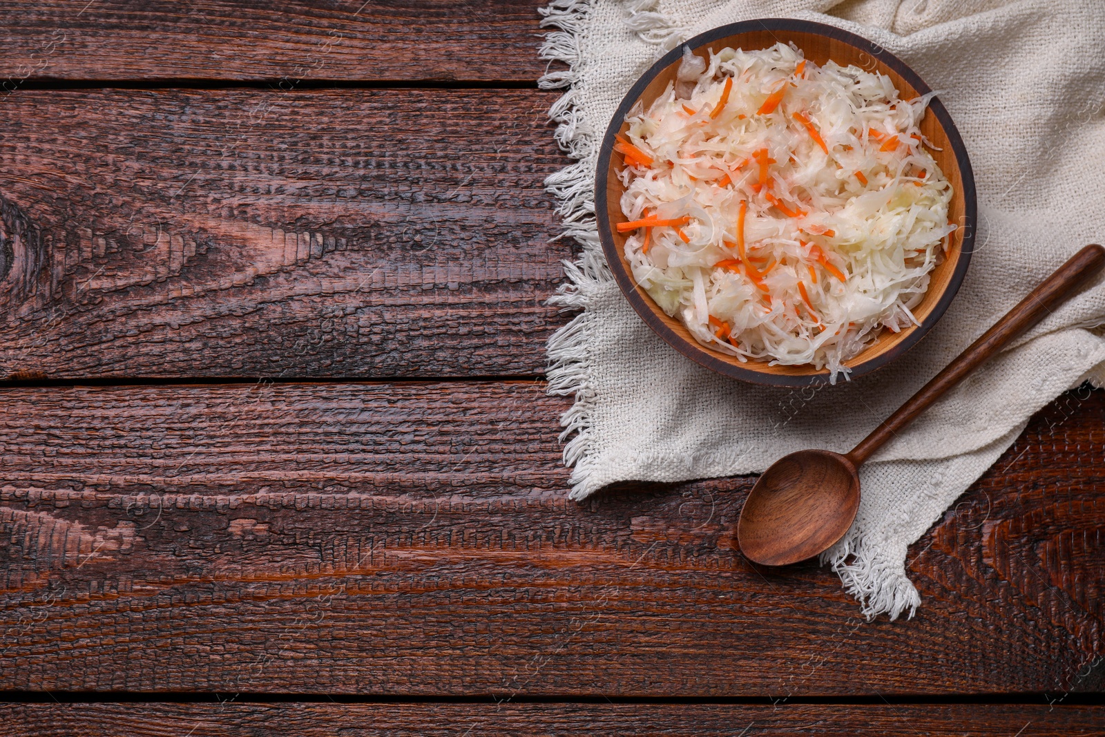 Photo of Bowl of tasty sauerkraut on wooden table, flat lay. Space for text