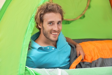 Young man in sleeping bag inside of tent