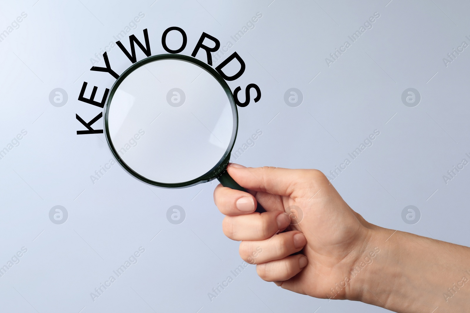 Image of Woman holding magnifying glass with word keyword, closeup