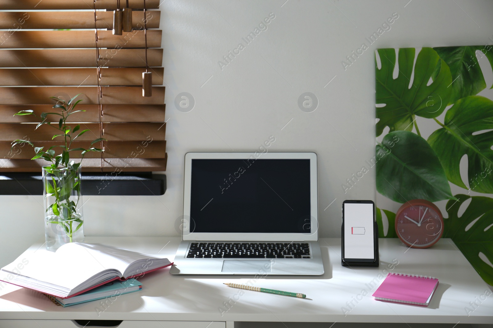 Photo of Modern workplace and smartphone charging with wireless pad