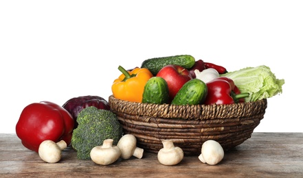 Photo of Wicker bowl with variety of fresh delicious vegetables and fruits on table against white background