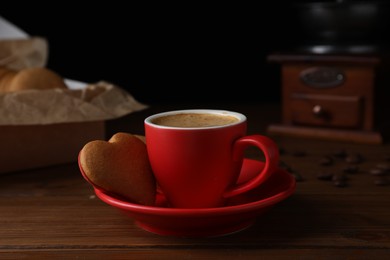 Delicious heart shaped cookies and cup of coffee on wooden table