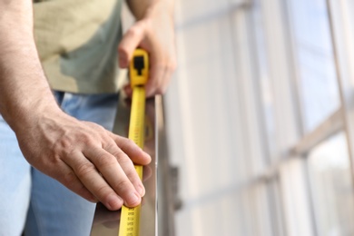 Man measuring metal railing, closeup view with space for text. Construction tool