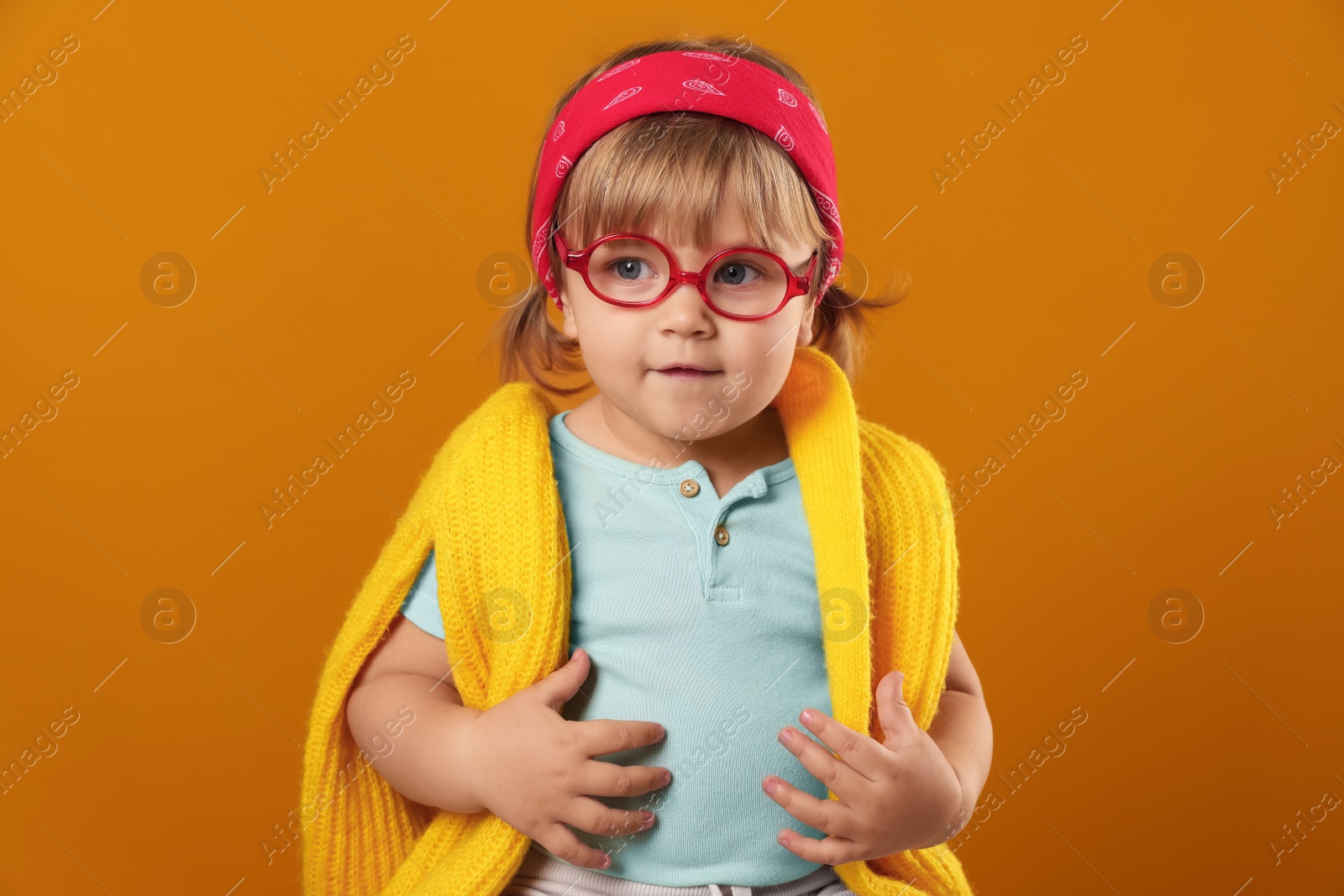 Photo of Cute little girl in glasses on orange background