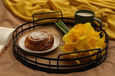 Photo of Bouquet of beautiful daffodils, bun and coffee on bed