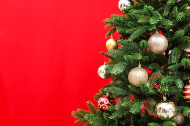 Photo of Beautifully decorated Christmas tree against color background, closeup