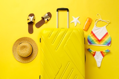 Photo of Flat lay composition with suitcase, bikini and beach accessories on color background