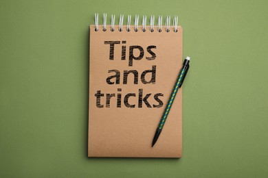 Image of Notebook with text Tips and tricks on green background, top view