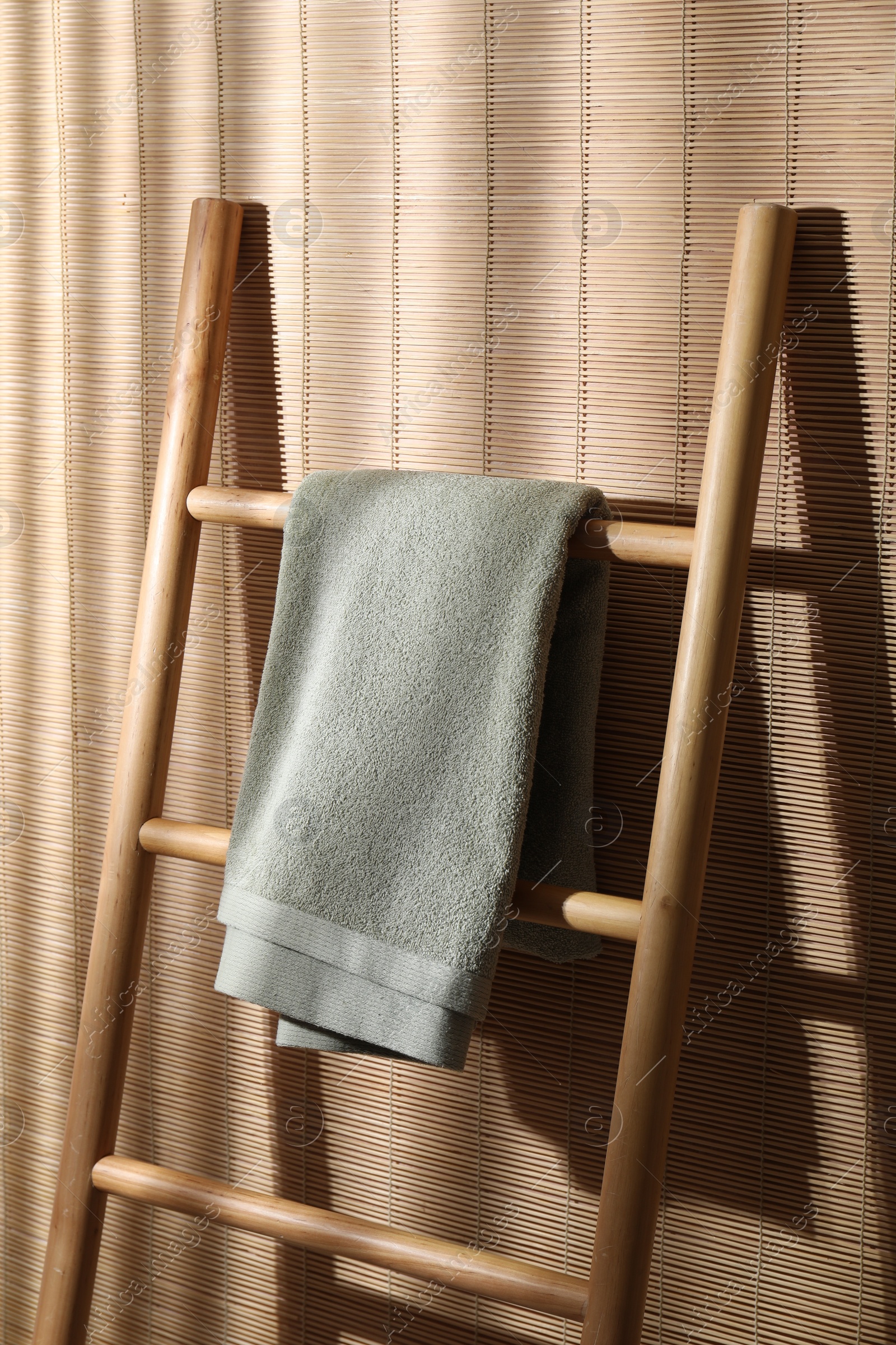 Photo of Green terry towel on wooden ladder indoors