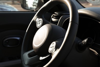 Photo of Black steering wheel inside of modern car, closeup