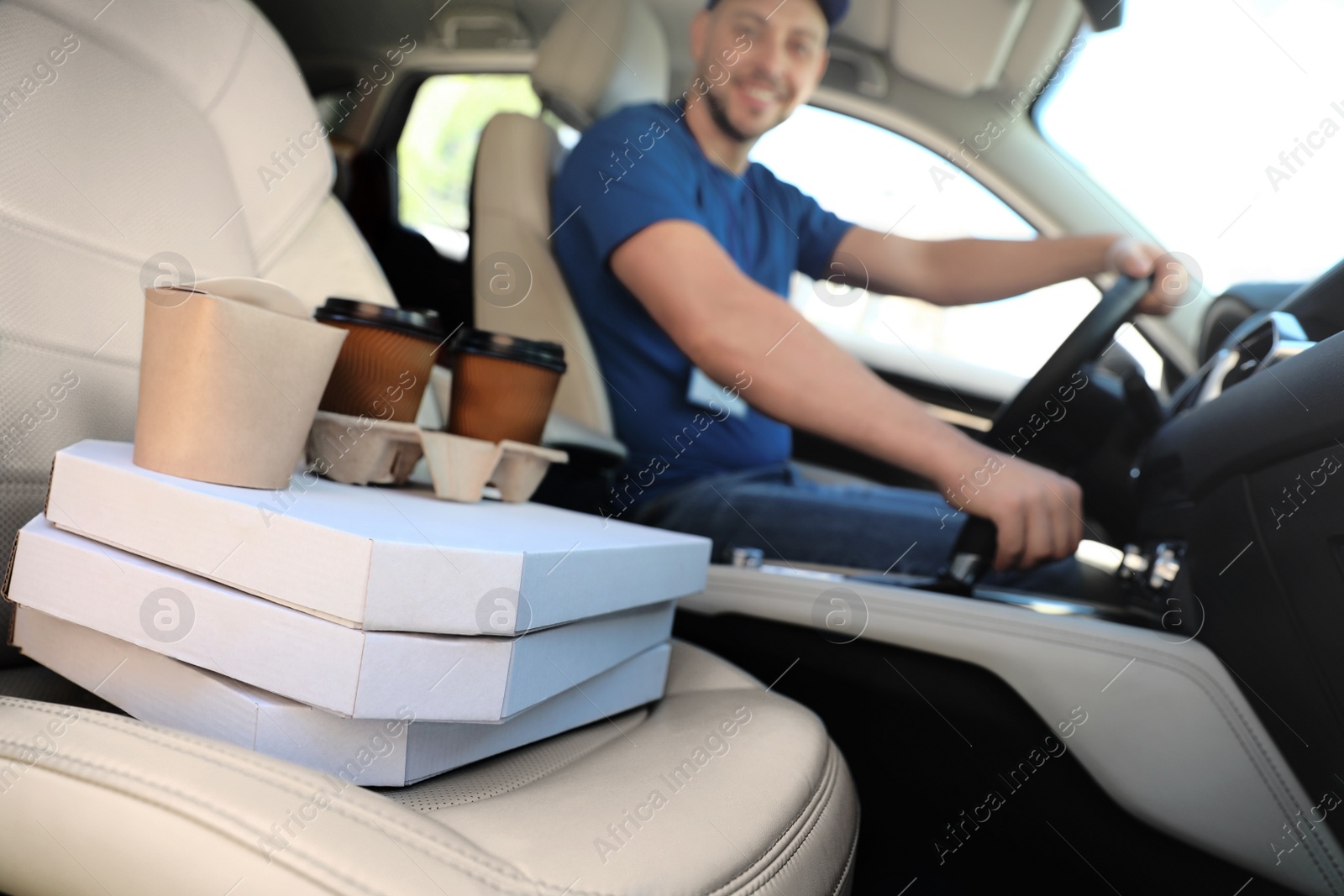 Photo of Male courier with orders in car. Food delivery service