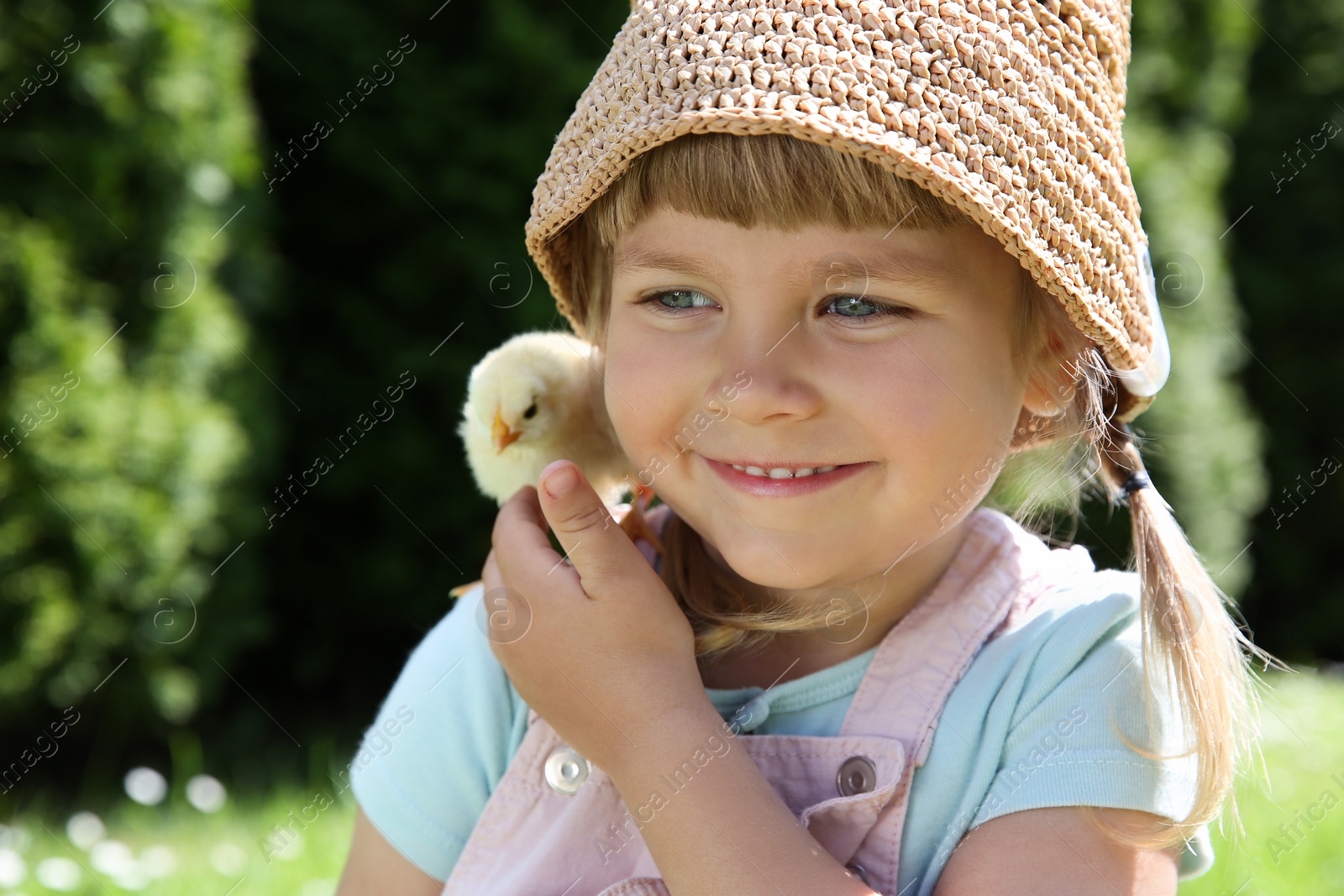 Photo of Cute little girl with chick outdoors. Baby animal