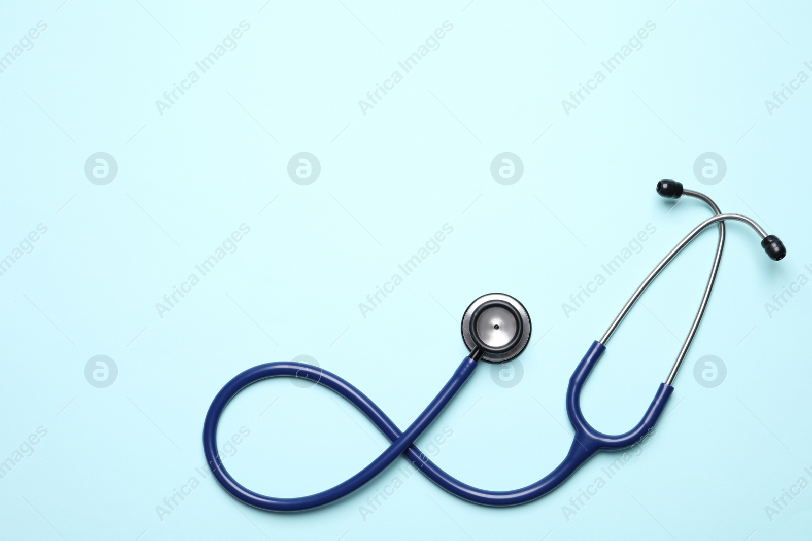 Photo of Stethoscope on light blue background, top view. Space for text